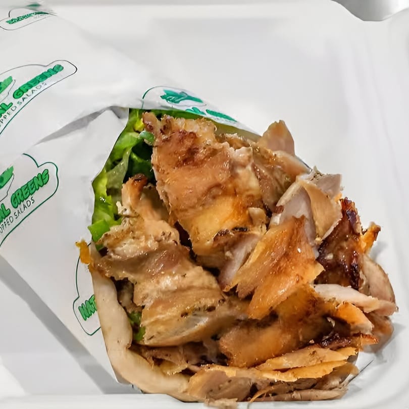 Natural Greens chicken and lettuce wrap in white paper, close-up.
