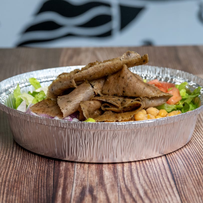 Natural Greens salad with sliced meat, chickpeas, lettuce, and tomatoes in a foil container.